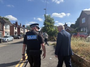 Police officer walking up a street with the Commissioner