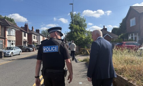 Police officer walking up a street with the Commissioner