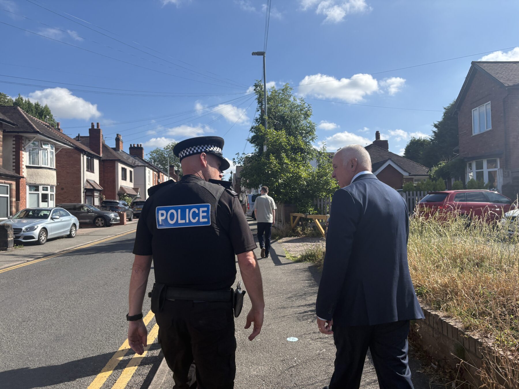 Police officer walking up a street with the Commissioner